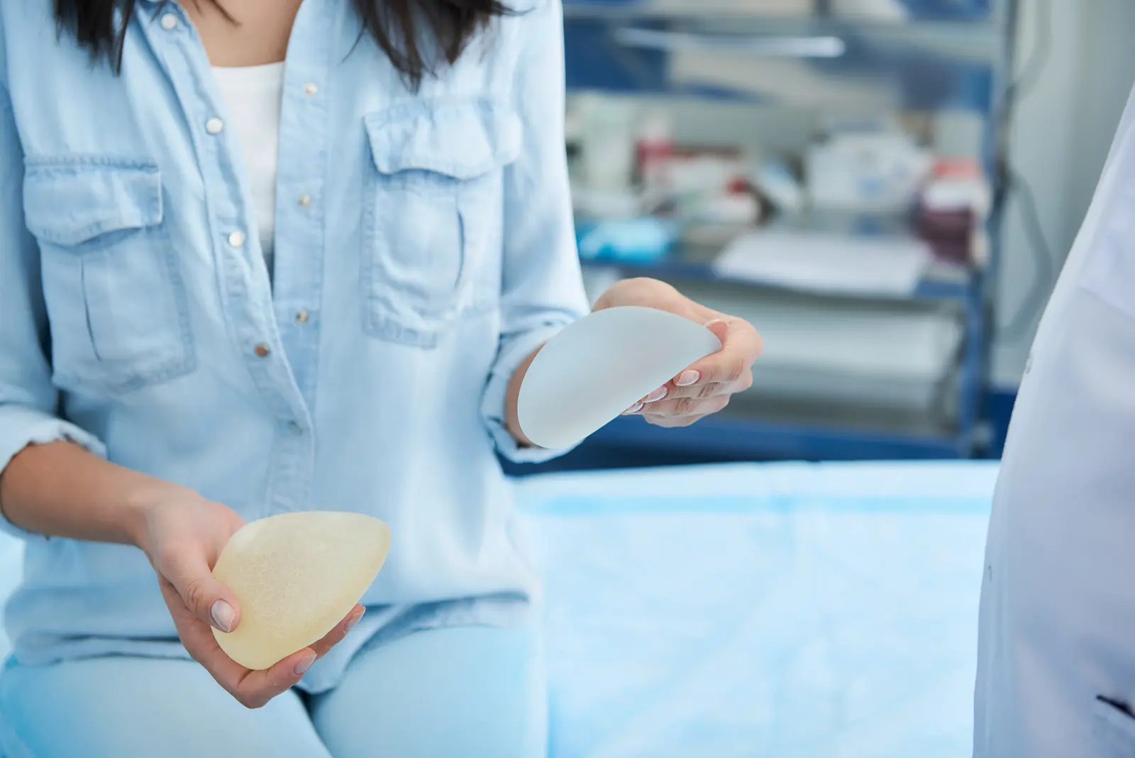 Person comparing silicone and saline breast implants in a medical office.